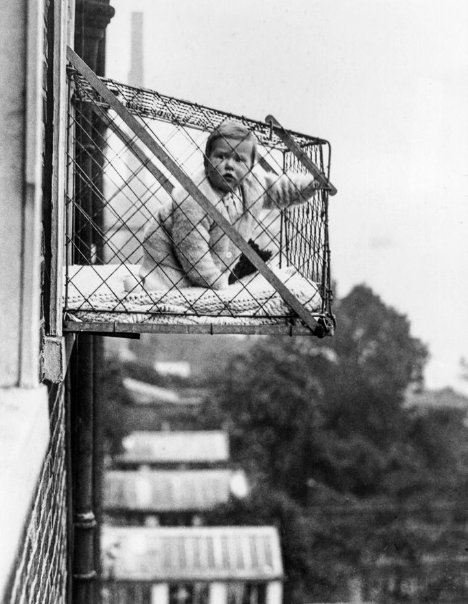 Fotografie z roku 1934 ukazuje drátěnou klec, kterou londýnská rada East Poplar navrhovala upevnit na okna činžovních domů, aby děti mohly být venku na čerstvém vzduchu.