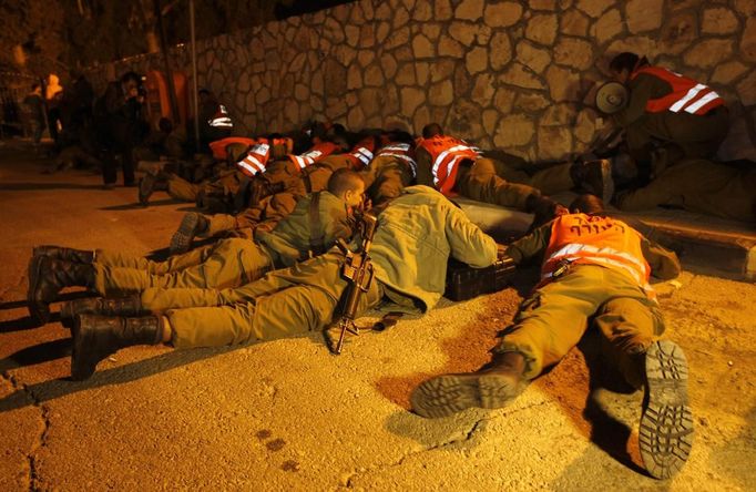 Israeli soldiers take cover as an air raid siren warns of incoming rockets before the funeral of Aaron Smadja, one of the three Israelis killed by a rocket fired from Gaza, at a cemetery in the southern city of Kiryat Malachi November 15, 2012. Two rockets fired from the Gaza Strip targeted Tel Aviv on Thursday in the first attack on Israel's commercial capital in 20 years, raising the stakes in a showdown between Israel and the Palestinians that is moving towards all-out war. REUTERS/Ronen Zvulun (ISRAEL - Tags: CIVIL UNREST POLITICS) Published: Lis. 15, 2012, 7:31 odp.