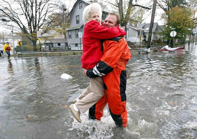 An emergency personnel carries an elderly resident from flood waters brought on by Hurricane Sandy in Little Ferry, New Jersey, October 30, 2012. Millions of people across the eastern United States awoke on Tuesday to scenes of destruction wrought by monster storm Sandy, which knocked out power to huge swathes of the nation's most densely populated region, swamped New York's subway system and submerged streets in Manhattan's financial district. REUTERS/Adam Hunger (UNITED STATES - Tags: DISASTER ENVIRONMENT) Published: Říj. 30, 2012, 4:02 odp.