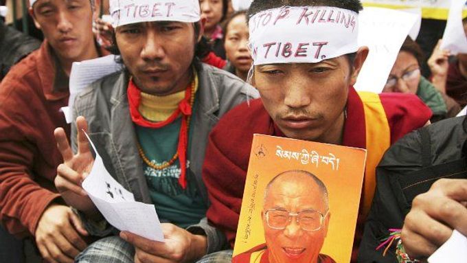 Tibetští demonstranti drží obrázek Dalajlámy.