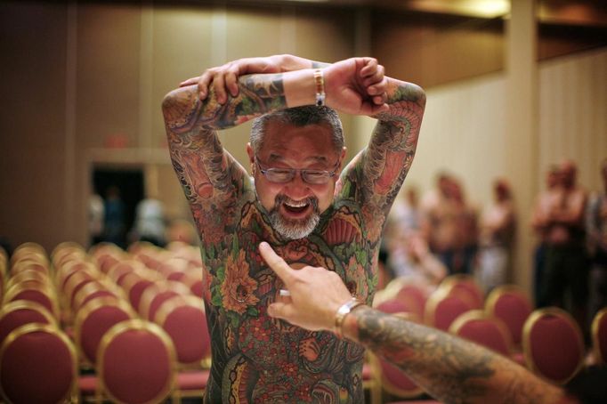 Contestant Yoshi shows off his full-body tattoo as a judge points to phallic symbols tattooed under his arm during judging at the National Tattoo Association Convention in Cincinnati, Ohio April 13, 2012. Yoshi, from Japan, was tattooed by Horiyoshi III and is a multi-award winning contestant in the world of full-body tattoos. In Cincinnati he won third place in the 'Best Tattooed Male' category. Picture taken April 13, 2012. REUTERS/Jason Reed (UNITED STATES - Tags: SOCIETY) ATTENTION EDITORS PICTURE 26 OF 31 FOR PACKAGE 'ADDICTED TO THE NEEDLE' TO FIND ALL PICTURES SEARCH 'ADDICTED NEEDLE' Published: Čer. 29, 2012, 1 odp.