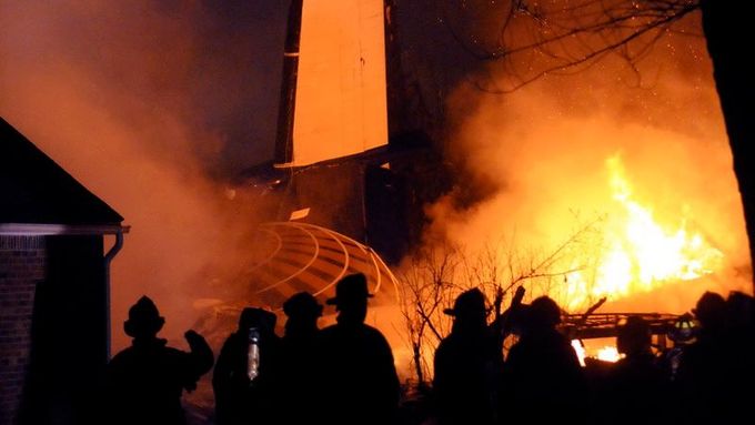 Hasiči se snaží zlikvidovat požár domu na předměstí Buffala, na který se zřítilo letadlo s bezmála padesáti lidmi na palubě.