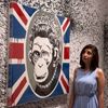 A gallery assistant poses with work &quot;Monkey Queen&quot; at the Banksy: The Unauthorised Retrospective at Sotheby's S2 Gallery in London