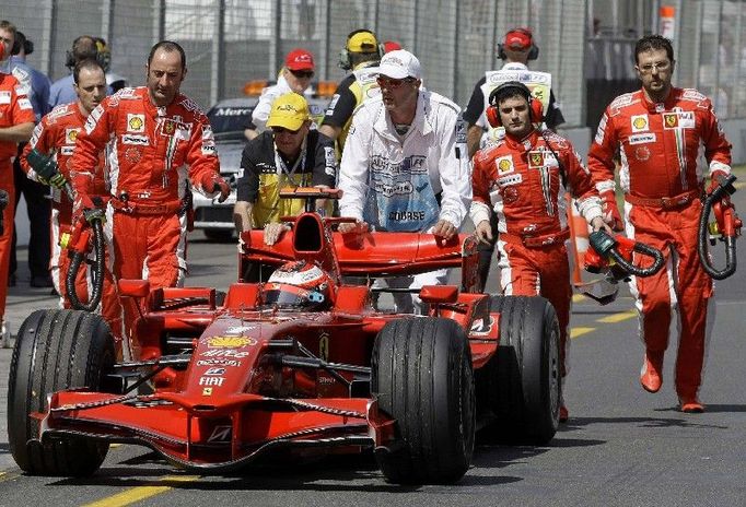 Mechanici tlačí do boxů porouchané Ferrari Kimi Räikkönena.