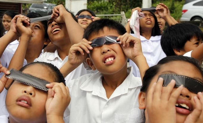 Filipino students use negative film strips to watch Venus passing between the Sun and the Earth in Silang, Cavite south of Manila June 6, 2012. Venus made a slow transit across the face of the sun on Tuesday, the last such passing that will be visible from Earth for 105 years. REUTERS/Erik De Castro (PHILIPPINES - Tags: SCIENCE TECHNOLOGY SOCIETY) Published: Čer. 6, 2012, 6:03 dop.