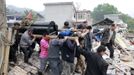 People lift a coffin as they walk past debris on their way to a funeral on the second day after an earthquake hit Longmen township of Lushan county, Sichuan province April 21, 2013. Rescuers struggled to reach a remote corner of southwestern China on Sunday as the toll of the dead and missing from the country's worst earthquake in three years climbed to 203 with more than 6,700 injured. REUTERS/China Daily (CHINA - Tags: DISASTER) CHINA OUT. NO COMMERCIAL OR EDITORIAL SALES IN CHINA Published: Dub. 21, 2013, 8:41 dop.