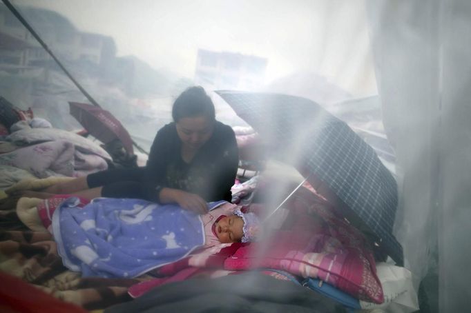 A woman looks at her child as they rest among the wreckage after Saturday's earthquake in Lingguan town of Baoxing county, Sichuan province, April 21, 2013. Rescuers struggled to reach a remote, rural corner of southwestern China on Sunday as the death toll climbs to 186 people dead and 11,393 injured, Xinhua News Agency reported. Picture taken April 21, 2013. REUTERS/China Daily (CHINA - Tags: DISASTER) CHINA OUT. NO COMMERCIAL OR EDITORIAL SALES IN CHINA Published: Dub. 22, 2013, 3:04 dop.