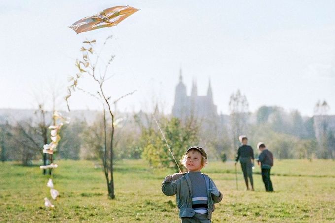 Dítě pouští papírového draka na Letenské pláni v Praze, v pozadí je vidět silueta Pražského hradu. Datum: 2. listopadu 1971. Kolorováno