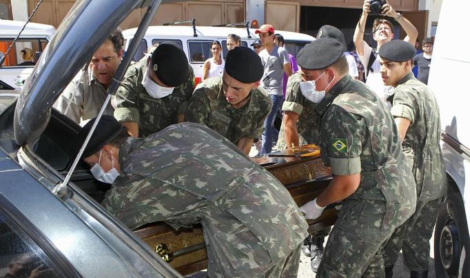 Army soldiers carry a coffin containing the body of a victim of the fire at Boate Kiss nightclub in the southern city of Santa Maria, 187 miles (301 km) west of the state capital of Porto Alegre, January 27, 2013. A fire in a nightclub killed at least 245 people in southern Brazil on Sunday when a band's pyrotechnics show set the building ablaze and fleeing patrons were unable to find the emergency exits in the ensuing panic, officials said. The blaze in the southern city of Santa Maria was started when a band member or someone from its production team ignited a flare, which then set fire to the ceiling, said Luiza Sousa, a civil police official. The fire spread "in seconds," she said. An estimated 500 people were in the Boate Kiss nightclub when the fire broke out early on Sunday, and many were unable to find the exits as dark smoke quickly filled the room. At least one exit was locked, trapping hundreds inside to die, many from asphyxiation as they inhaled smoke, police said. REUTERS/Edison Vara (BRAZIL - Tags: DISASTER MILITARY) Published: Led. 27, 2013, 8:01 odp.