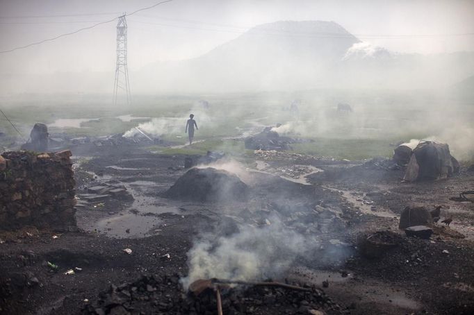 A man walks past heaps of burning coal to make it for domestic use such as for cooking purposes at Dhanbad district in the eastern Indian state of Jharkhand September 20, 2012. With oil and gas output disappointing and hydropower at full throttle, Asia's third-largest economy still relies on coal for most of its vast energy needs. About 75 percent of India's coal demand is met by domestic production and, according to government plans, that won't change over the next five years. Picture taken September 20, 2012. To match INDIA-COAL/ REUTERS/Ahmad Masood (INDIA - Tags: BUSINESS EMPLOYMENT ENERGY SOCIETY ENVIRONMENT) Published: Říj. 21, 2012, 10:03 odp.