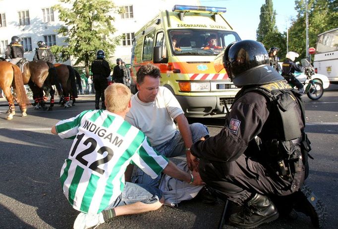 Chvíli také létaly vzduchem plastové i skleněné lahve. Muže v bílém tričku pořezala jedna z nich na kotníku.