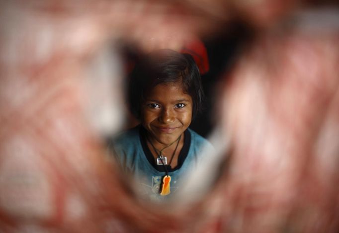 Shivani Choudhary, 7, a street performer drinks tea outside her hut at a slum on the bank of Manahara River before leaving to perform on the streets of Kathmandu August 15, 2012. Shivani and her brothers Drumpal and Gchan, who came to Kathmandu from India 5 years ago, earn their living by performing tricks on the streets of Kathmandu. According to Drumpal, Shivani's older brother, they earn around $10 a day by performing tricks, which is not enough to feed their 10-member family living together in a small hut without a proper toilet or any basic needs. REUTERS/Navesh Chitrakar (NEPAL - Tags: SOCIETY IMMIGRATION POVERTY) Published: Srp. 15, 2012, 3:59 odp.