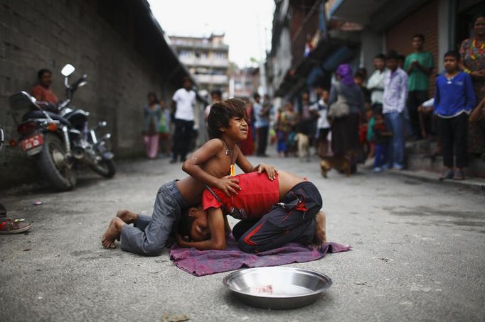 People watch as Shivani Choudhary, 7, and her brother Drumpal, 11, perform tricks on a street in Kathmandu August 15, 2012. Shivani, Drumpal and their brother Gchan, who came to Kathmandu from India 5 years ago, earn their living by performing tricks on the streets of Kathmandu. According to Drumpal, Shivani's older brother, they earn around $10 a day by performing tricks, which is not enough to feed their 10-member family living together in a small hut without a proper toilet or any basic needs. REUTERS/Navesh Chitrakar (NEPAL - Tags: SOCIETY POVERTY IMMIGRATION) Published: Srp. 15, 2012, 4:41 odp.