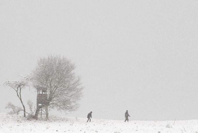 People walk through a snowy landscape near the village of Dorndorf-Steudnitz in the south-eastern German state of Thuringia, October 27, 2012. REUTERS/Thomas Peter (GERMANY - Tags: ENVIRONMENT TPX IMAGES OF THE DAY) Published: Říj. 27, 2012, 1:27 odp.