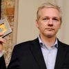 Julian Assange drží v ruce dokumenty k WikiLeaks