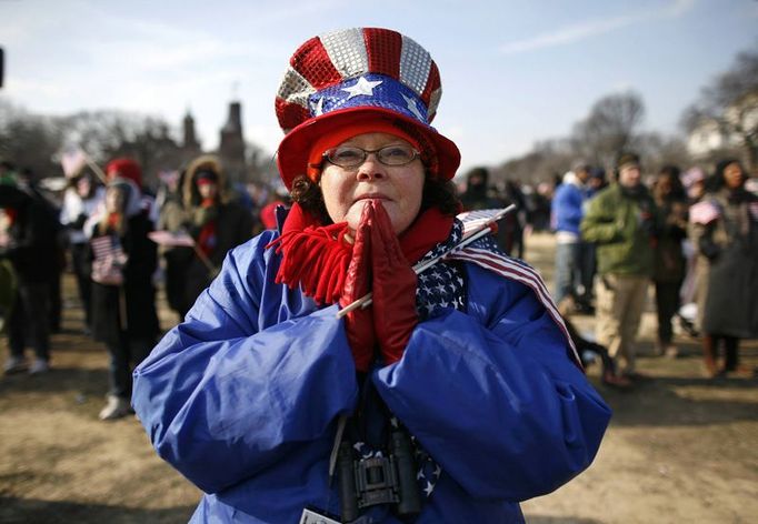 Co nás s novým prezidentem čeká? Američanka sleduje modlitbu během inauguračního ceremoniálu Baracka Obamy.