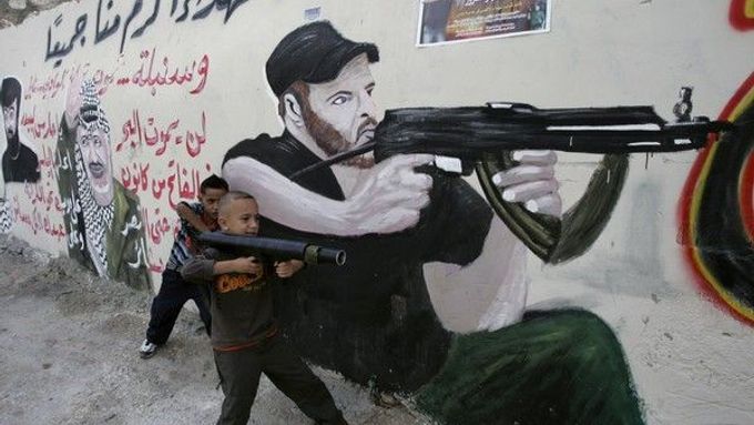 Pomalovaná zeď a chlapci hrající si na vojáky na Západním břehu Jordánu (ilustrační foto).