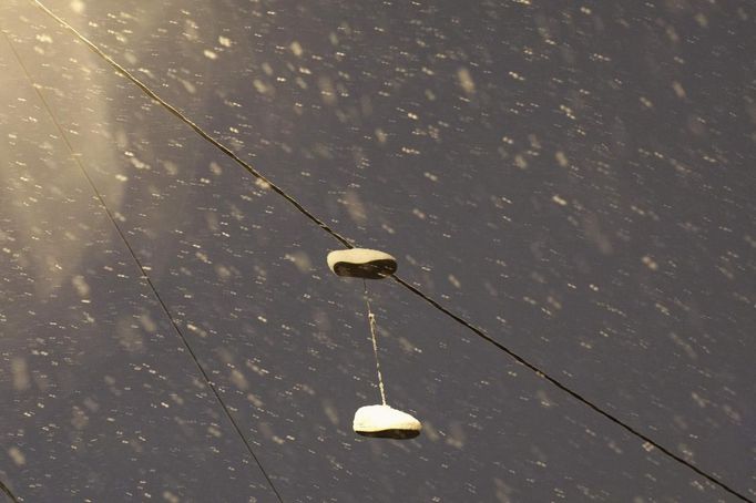 Sneakers are seen hanging from an electricity wire under snow during the nor'easter, also known as a northeaster storm, in Jersey City, New Jersey, November 7, 2012. A wintry storm dropped snow and rain on the U.S. Northeast on Wednesday, bringing dangerous winds and knocking out power in a region where hundreds of thousands were still in the dark after Superstorm Sandy. REUTERS/Eduardo Munoz (UNITED STATES - Tags: ENVIRONMENT DISASTER) Published: Lis. 8, 2012, 2:49 dop.