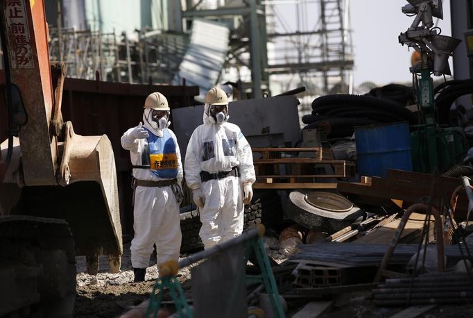 Workers wearing protective suits and masks are seen next to the No.4 reactor at Tokyo Electric Power Company's (TEPCO) tsunami-crippled Fukushima Daiichi nuclear power plant in Fukushima prefecture March 6, 2013, ahead of the second-year of anniversary of the the March 11, 2011 tsunami and earthquake. REUTERS/Issei Kato (JAPAN - Tags: DISASTER ANNIVERSARY) Published: Bře. 6, 2013, 10:33 dop.