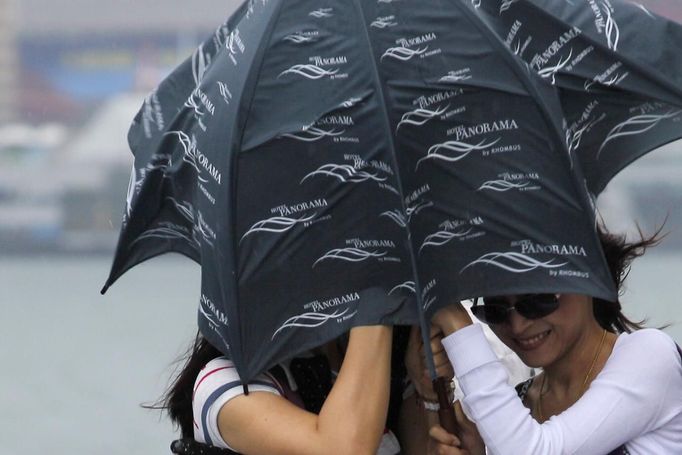 Women brave strong winds at the Tsim Sha Tsui district after Typhoon Vicente hit Hong Kong July 24, 2012. A severe typhoon hit Hong Kong on Tuesday, disrupting business across the financial hub, with offices and the stock market to remain closed for at least part of the morning after the city raised its highest typhoon warning overnight. REUTERS/Tyrone Siu (CHINA - Tags: ENVIRONMENT DISASTER BUSINESS) Published: Čec. 24, 2012, 3:06 dop.