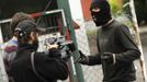 A masked coal miner (R) speaks to media at the main gate of Pozo Santiago mine in Caborana, near Oviedo, northern Spain June 18, 2012. Spanish coal mining unions are taking part in a general strike in northern Spain mining areas as they are protesting against government action to cut coal subsidies. REUTERS/Eloy Alonso (SPAIN - Tags: CIVIL UNREST BUSINESS EMPLOYMENT ENERGY MEDIA) Published: Čer. 18, 2012, 11:25 dop.