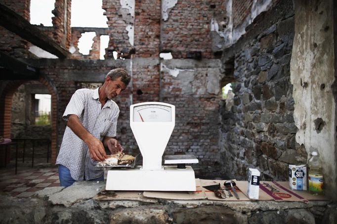 Nedzad Begovic looks at a scale in a restaurant in Potocari, near Srebrenica, July 6, 2012. Begovic and Slobodan Radakovic, both war survivors, make a living by putting together a restaurant selling roasted lamb. During the war, Bosnian Serb forces commanded by General Ratko Mladic killed up to 8000 Muslim men and boys in the Srebrenica area. Begovic lost 70 family members and Radakovic lost 10 family members. Picture taken July 6, 2012. REUTERS/Dado Ruvic (BOSNIA AND HERZEGOVINA - Tags: CONFLICT SOCIETY FOOD) Published: Čec. 8, 2012, 3:23 dop.