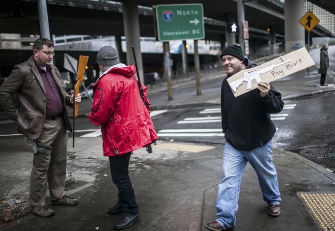 David Carnahan (L) looks over a rifle before buying it outside of the Seattle Police Department gun buyback event, as another buyer passes in Seattle, Washington January 26, 2013. Participants received up to a $100 gift card in exchange for working handguns, shotguns and rifles, and up to a $200 gift card for assault weapons. The event lasted from 9 a.m. until shortly after noon, after the event ran out of $80,000 worth of gift cards. REUTERS/Nick Adams (UNITED STATES - Tags: POLITICS CIVIL UNREST) Published: Led. 27, 2013, 12:48 dop.