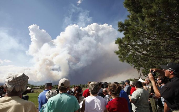 Evacuated residents and others listen to a briefing as smoke rises from the Waldo Canyon fire west of Colorado Springs, Colorado June 26, 2012. A fast-growing wildfire in Colorado forced 11,000 people from their homes at least briefly and threatened popular summer camping grounds beneath Pikes Peak, whose vistas helped inspire the patriotic tune "America the Beautiful". REUTERS/Rick Wilking (UNITED STATES - Tags: DISASTER ENVIRONMENT) Published: Čer. 26, 2012, 10:44 odp.