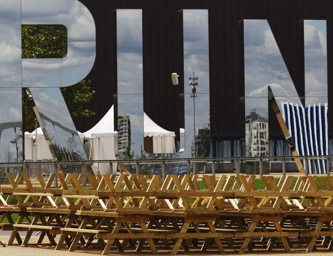 Picnic tables are stored next to a large mirrored word "RUN" in the London 2012 Olympic Park at Stratford in London July 12, 2012. Preparations for the London Olympics have put Britain's intelligence agencies under significant pressure, as the country stages its largest ever peacetime security operation, MPs said on Thursday. REUTERS/Luke MacGregor (BRITAIN - Tags: SPORT OLYMPICS) Published: Čec. 12, 2012, 6:29 odp.