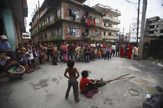 Nepalese people watch as Shivani Choudhary, 7, and her brother Drumpal, 11, perform tricks on a street in Kathmandu August 15, 2012. Shivani and her brothers Drumpal and Gchan, who came to Kathmandu from India 5 years ago, earn their living by performing tricks on the streets of Kathmandu. According to Drumpal, Shivani's older brother, they earn around $10 a day by performing tricks, which is not enough to feed their 10-member family living together in a small hut without a proper toilet or any basic needs. REUTERS/Navesh Chitrakar (NEPAL - Tags: SOCIETY IMMIGRATION POVERTY) Published: Srp. 15, 2012, 4:30 odp.