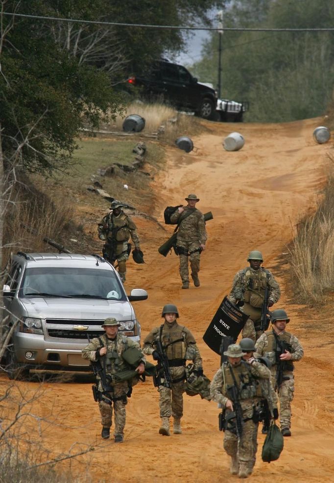 Law enforcement personnel walk away from the perimeter of the scene of a shooting and hostage taking in Midland City, Alabama, January 30, 2013. A gunman boarded an Alabama school bus ferrying children home from school on Tuesday and fatally shot the driver before fleeing with a young child and holing up in an underground bunker, Alabama media reported. Sheriff's officials confirmed that one person had been killed in a shooting involving a school bus in Alabama's Dale County but gave scant details other than to say that a child was present at the scene in Midland City. REUTERS/Phil Sears (UNITED STATES - Tags: CRIME LAW) Published: Led. 30, 2013, 10:54 odp.