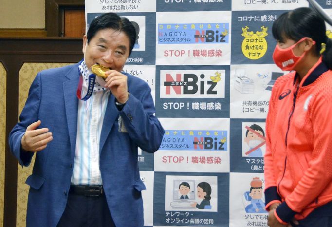 FILE PHOTO: Nagoya city Mayor Takashi Kawamura bites the Tokyo 2020 Olympic Games gold medal of the softball athlete Miu Goto during a ceremony in Nagoya, central Japan,