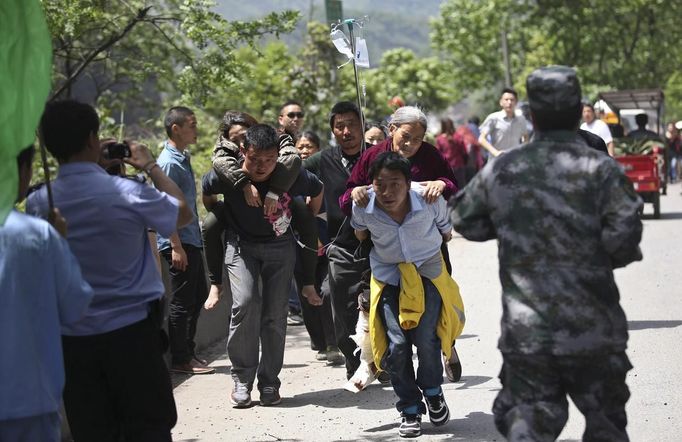 Men carry injured people to an ambulance at Longmen Village, Lushan county, Ya'an, Sichuan province, April 20, 2013. A strong 6.6 magnitude earthquake hit a remote, mostly rural and mountainous area of southwestern China's Sichuan province on Saturday, killing at least 102 people and injuring about 2,200 close to where a big quake killed almost 70,000 people in 2008. REUTERS/Stringer (CHINA - Tags: DISASTER) CHINA OUT. NO COMMERCIAL OR EDITORIAL SALES IN CHINA Published: Dub. 20, 2013, 9:11 dop.