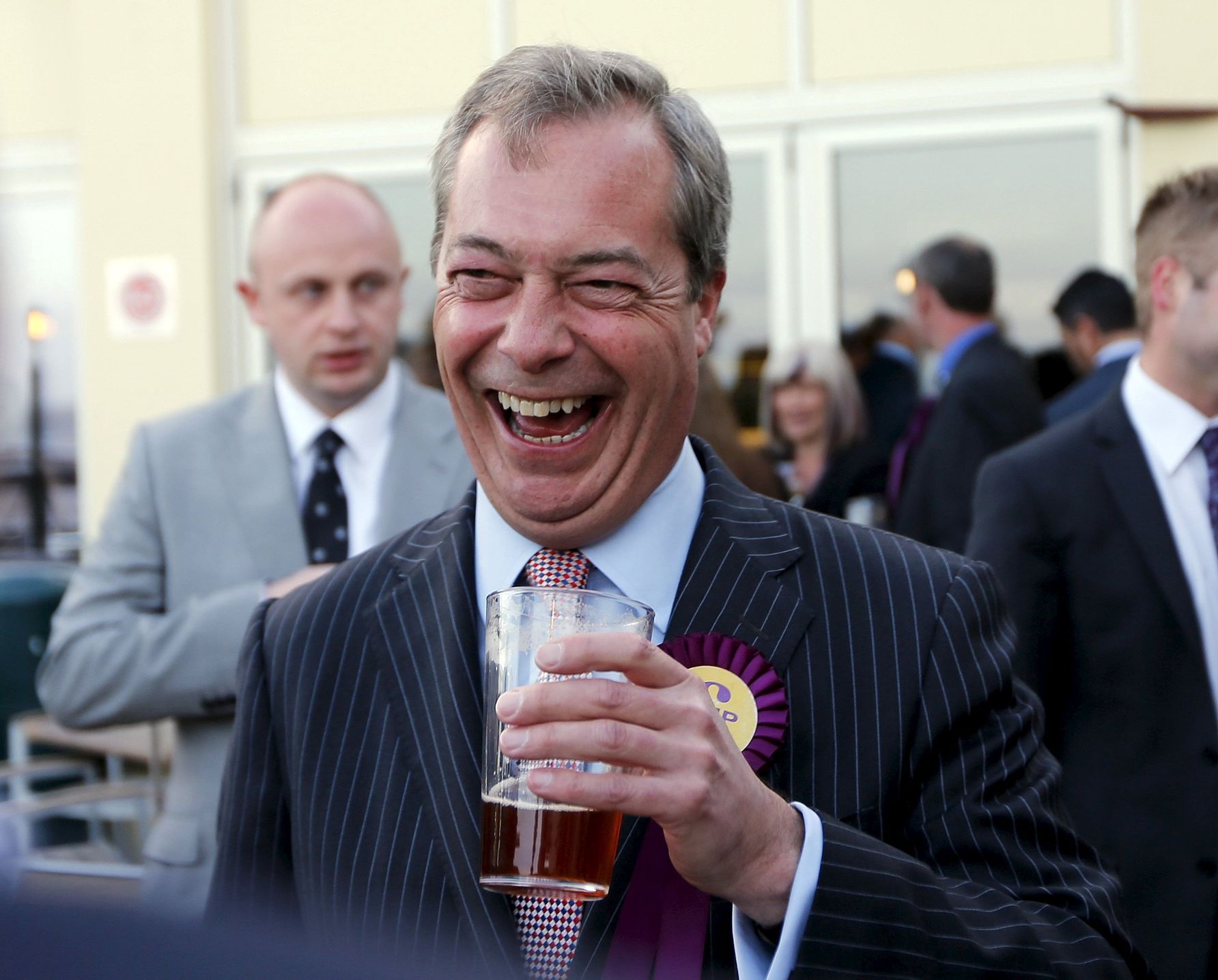 Leader of the United Kingdom Independence Party Nigel Farage laughs as he holds a pint of beer after arriving for a campaign event in Broadstairs