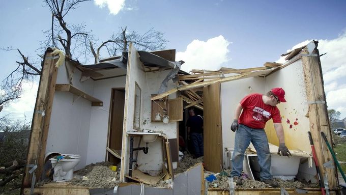 A man picks up debris from a damaged home in Thurman, Iowa