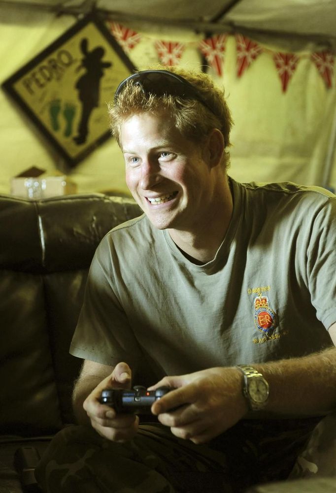 Britain's Prince Harry plays a computer soccer game with fellow Apache crew at Camp Bastion, southern Afghanistan in this photograph taken November 3, 2012, and released January 21, 2013. The Prince, who is serving as a pilot/gunner with 662 Squadron Army Air Corps, is on a posting to Afghanistan that runs from September 2012 to January 2013. Photograph taken November 3, 2012. REUTERS/John Stillwell/Pool (AFGHANISTAN - Tags: MILITARY POLITICS SOCIETY MEDIA ROYALS CONFLICT) Published: Led. 21, 2013, 8:57 odp.