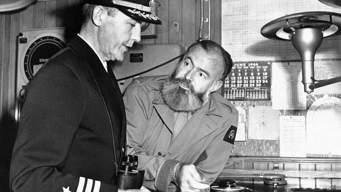 Ernest Hemingway (vpravo) pózuje 4. července 1944 nad mapami použitými pro spojeneckou invazi do Evropy.