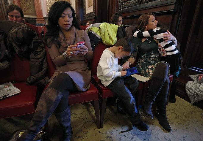 Theresa Volpe (2nd R) sits with her daughter Ava (R) and son Jaidon (3rd R) while her partner Mercedes Santos responds to emails as they wait for the start of an an Illinois Senate Executive Committee hearing on same-sex marriages at the State Legislature in Springfield, Illinois, January 3, 2013. Santos and Volpe are a same-sex couple raising two of their biological children as they struggle to get same-sex marriages passed into law in Illinois. Picture taken on January 3, 2013. REUTERS/Jim Young (UNITED STATES - Tags: SOCIETY) Published: Bře. 25, 2013, 6:07 odp.