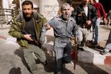 Zraněnému příslušníkovi policejních složek Hamásu pomáhá jeden z jeho kolegů
