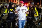 Nedaleko budovy portlandské ICE zatýkají policisté muže, který zůstal na místě, i když většina davu se už rozprchla. Je slyšet jen vzdálené houkání sirén.