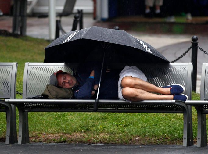 Tenisový fanoušek na US Open 2012 odpočívá během deště.