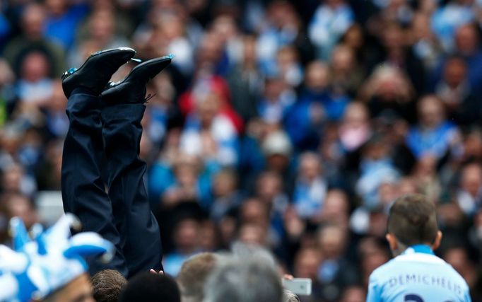 Manchester City's manager Manuel Pellegrini is thrown into the air by his team as they celebrate winning the English Premier League trophy following their soccer match ag