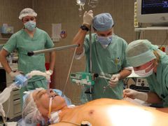 20:56 Anesteziologický tým zavádí poslední kanylu do pacientovy paže. Páni chirurgové, můžete začít.