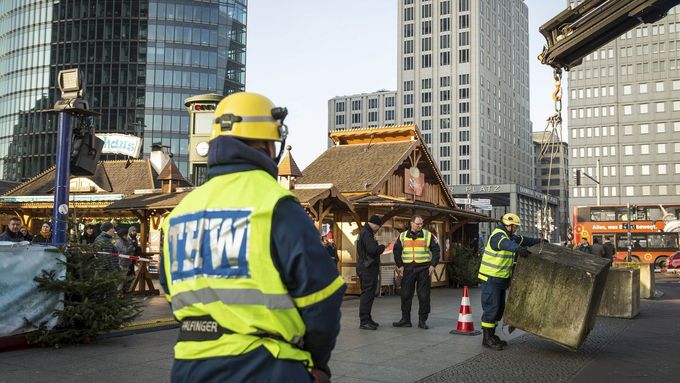 Technici instalují betonové bloky kolem vánočního trhu na Potsdamer Platz v Berlíně.