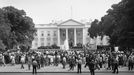 Prezident Dwight Eisenhower se zastavuje ve dveřích severního portika Bílého domu, aby zamával davům u železné brány po návratu ze summitu, 20. května 1960.