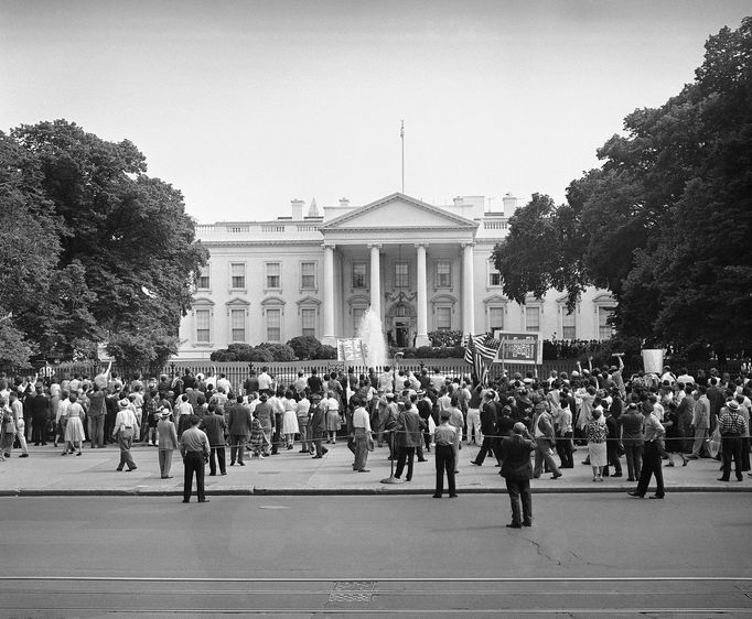 Prezident Dwight Eisenhower se zastavuje ve dveřích severního portika Bílého domu, aby zamával davům u železné brány po návratu ze summitu, 20. května 1960.