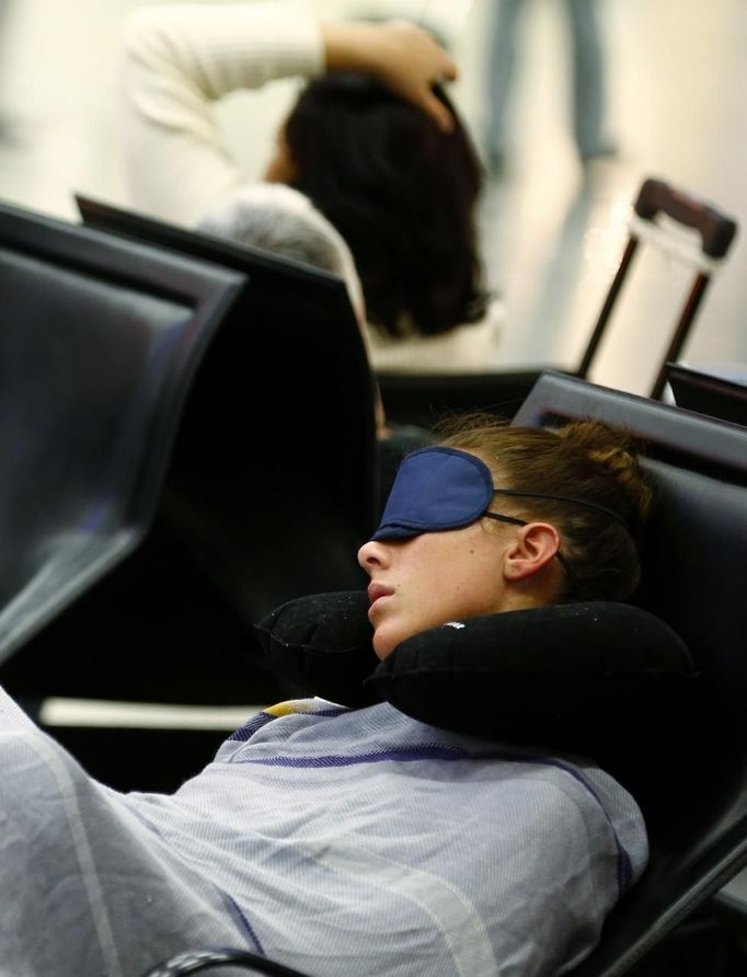 A passenger rests, wrapped in the blankets of German air carrier Lufthansa as they wait for their transfer at the Fraport airport in Frankfurt, September 4, 2012. Lufthansa passengers face widespread flight disruption after cabin crew representatives said they continue a series of strikes over pay and cost-cutting measures at Germany's largest airline. The UFO union, which represents around two-thirds of Lufthansa's 19,000 cabin crew, late on Thursday called on its members to strike from 0400 GMT to 1500 GMT on Tuesday in Frankfurt and Berlin's Tegel airport from 0300-1100 GMT. REUTERS/Kai Pfaffenbach (GERMANY - Tags: BUSINESS EMPLOYMENT CIVIL UNREST TRANSPORT) Published: Zář. 4, 2012, 8:41 dop.