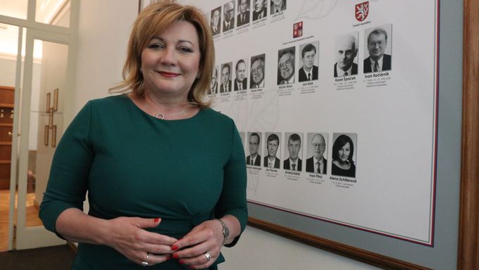 Alena Schillerová stojí před fotografiemi všech ministrů financí od vzniku Československa v roce 1918. Za více než 100 let je první ženou na tomto postu.