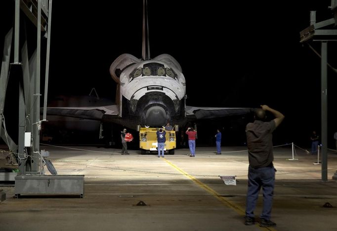 Workers take photos before the space shuttle Discovery is lifted at the Mate Demate Facility at Kennedy Space Center