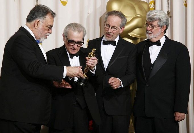 Režisér Martin Scorsese ukazueje Oscara ostatním režisérům. Zlatou sošku obdivuje Francis Ford Coppola, George Lucas a Steven Spielberg.